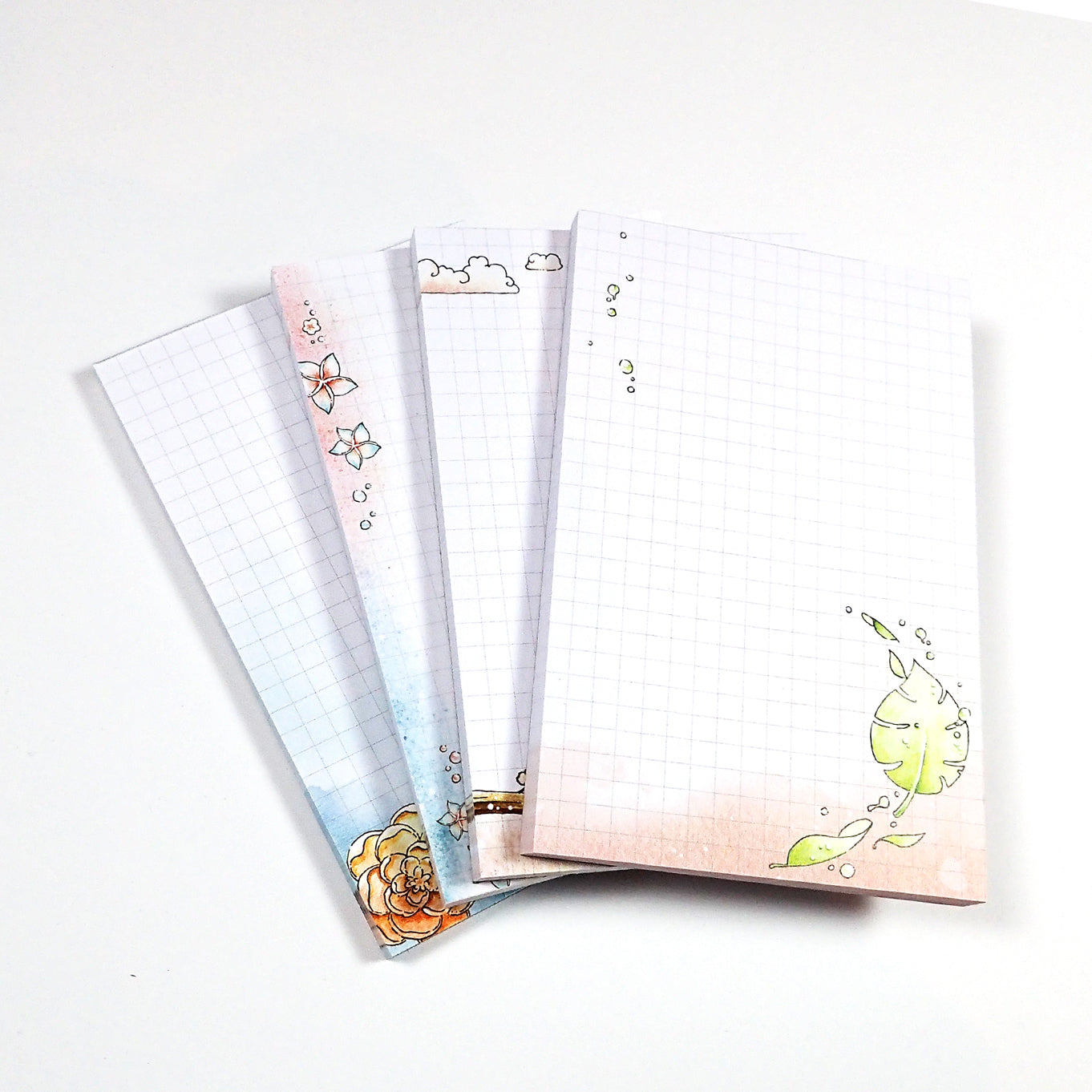 Four watercolored grid notepads pocket sized